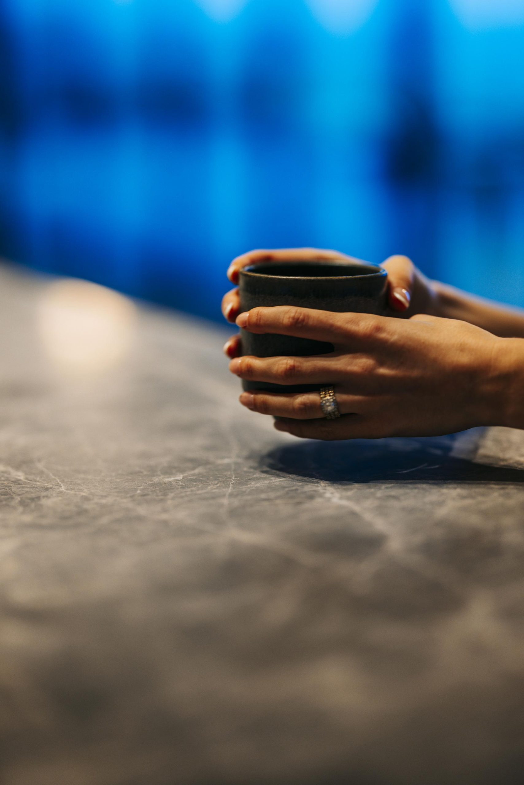 Hands cradle a cup over the edge of a table